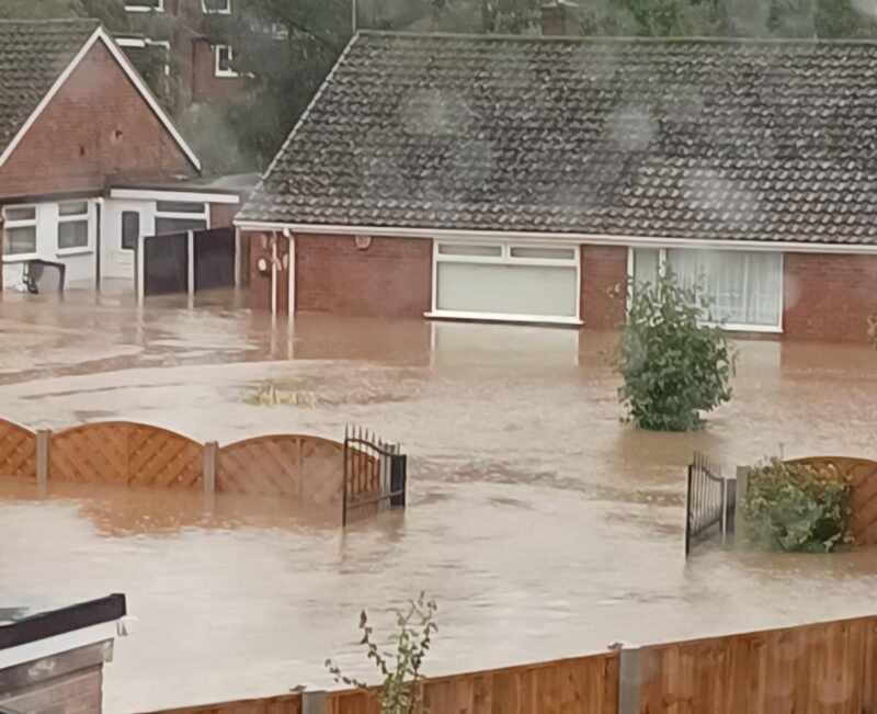 Photo of houses half submerged in brown water.